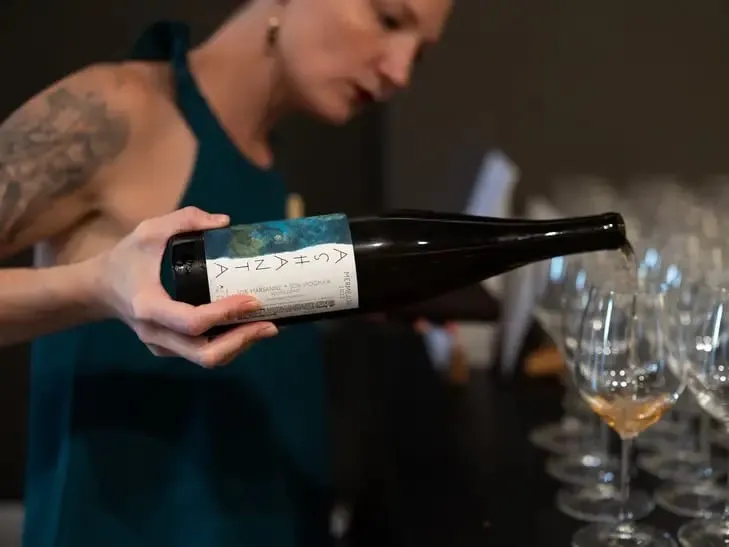 Ali pouring white wine into rows of tasting glasses