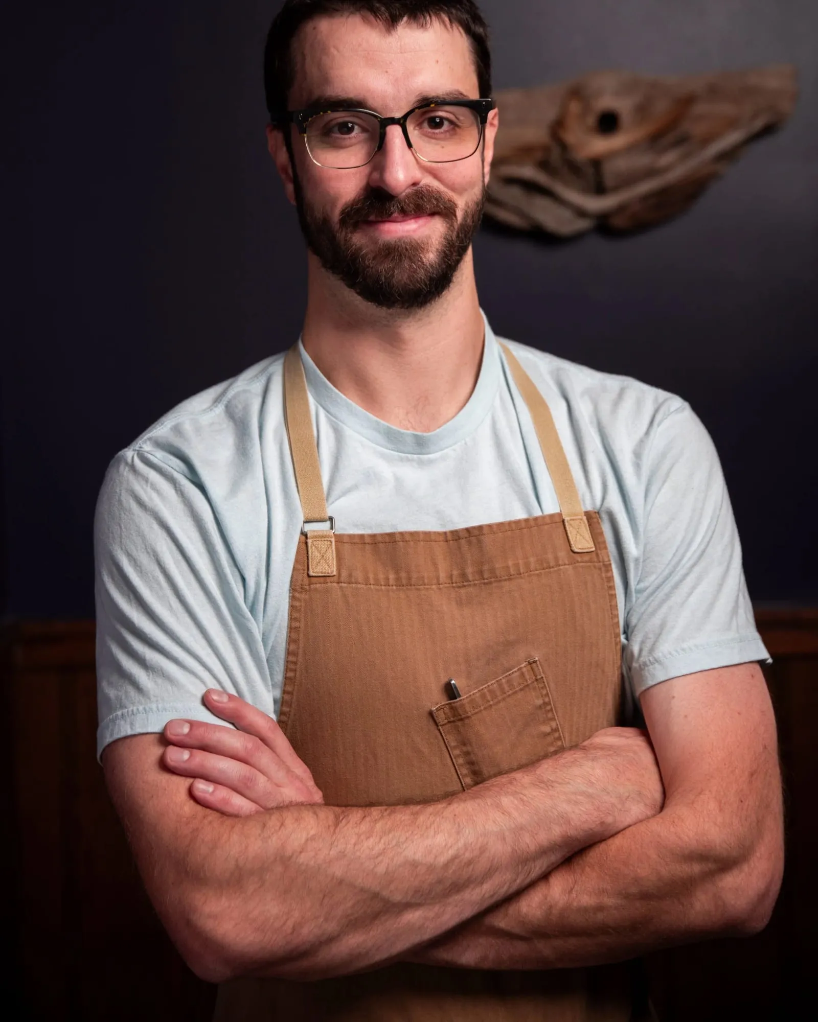 Bradyn Kawcak, arms crossed in a chef’s apron